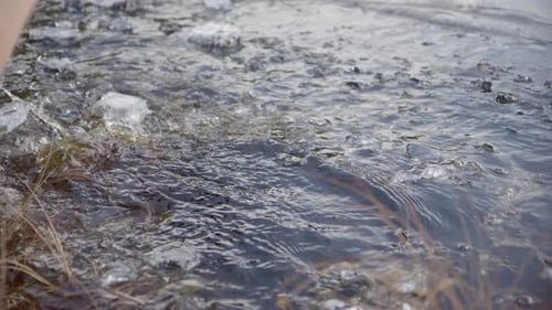 Hand Holding Ice in Flowing Water