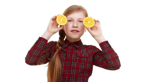 Girl Holds Orange Slices to Eyes in Studio
