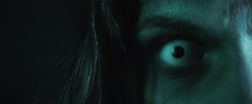 Terrifying creepy zombie woman, close up of white eye opening. Scary look.