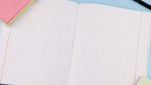 Schulmaterial mit Notizblock liegt auf einem pastellblauen Hintergrund mit einer medizinischen Maske