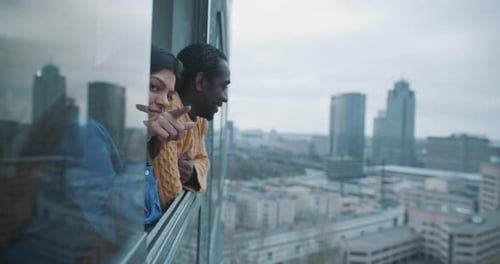 Man and Woman Look Over City From Window