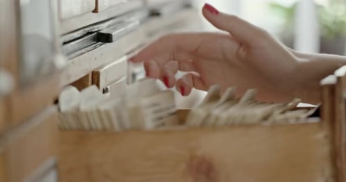 Crop Medium Shot of Female Hand Looking for and Finding Cards with Information in Index in Library