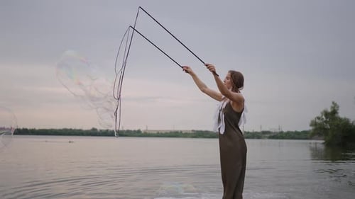 Woman Makes Giant Soap Bubbles by Lake
