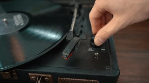 A close-up shot of a hand turning on a turntable and placing the needle on the record.