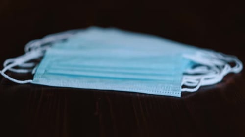 Light Blue Medical Face Masks Stacked on Dark Table