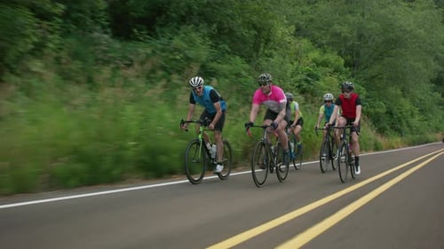 Tracking-Aufnahme einer Gruppe von Radfahrern auf einer Landstraße. Vollständig für den kommerziell Gebrauch freigegeben.