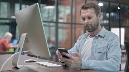 Man Using Mobile Phone at Desk in Office