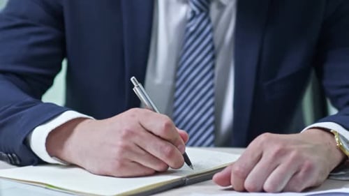 Businessman Writing in Notebook
