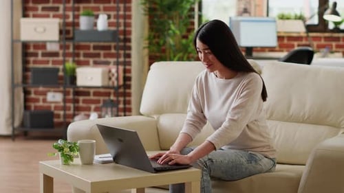 Woman Using Laptop Computer on Couch at Home