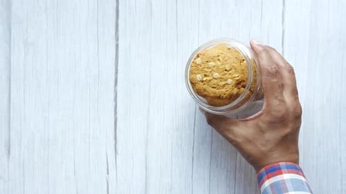 Hand Taking a Cookie from a Container