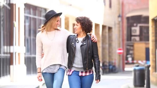 Multiracial gay couple walking embraced in London, talking and having fun tog