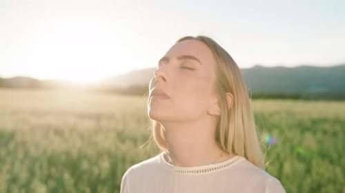 Close up shot of young woman with closed eyes enjoying sunbeams in rural nature