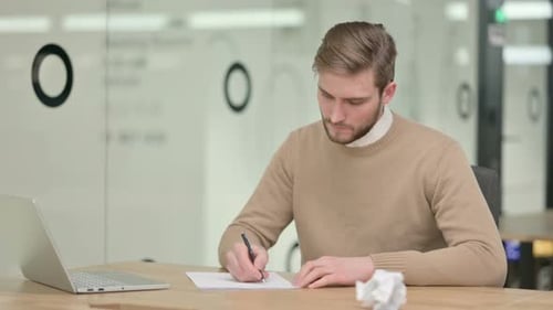 Man Writes at Desk in Bright Modern Workplace