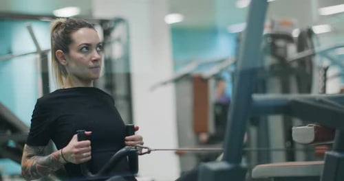 Woman Exercising with Rowing Machine at gym.Front View, Slow Motion. Woman Training at Rowing