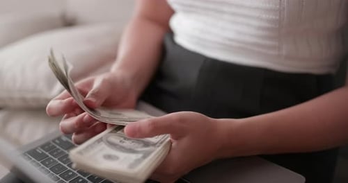 Close-up hands of woman counting many banknote in hands