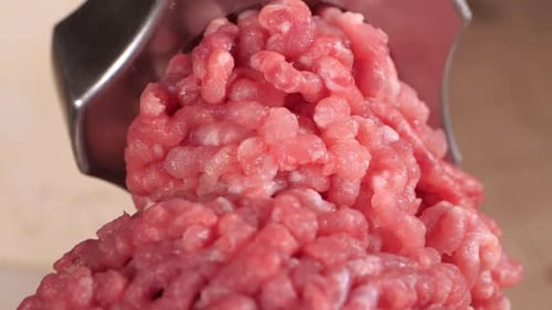 O recheio sai por uma peneira de moedor de carne. Moedor de carne Close Up, pilha de carne picada, picador