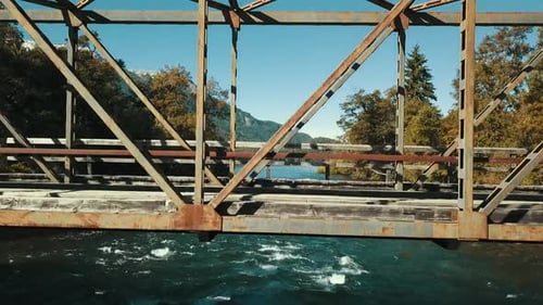 Die Drohne steigt aus dem Wasser auf die Spitze einer alten Metallbrücke, um die Herbstlandschaft mit dem La zu sehen