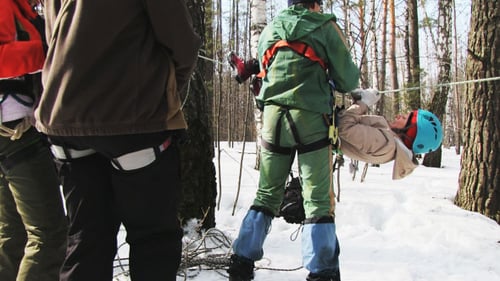 Person Suspended Upside Down from Winter Forest Rope