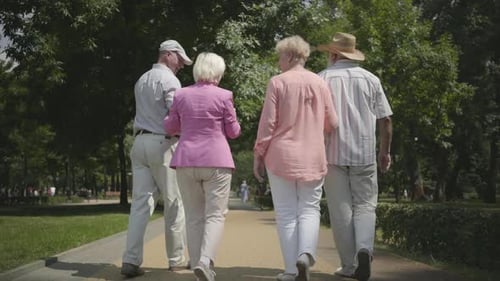 Two Adorable Mature Couples Walking and Talking in the Park