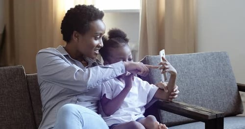 Woman and Child Using Smartphone Together on Couch