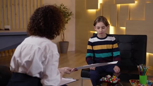 Child in Therapy Session Showing Drawing to Adult