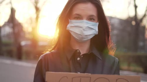 Young Adult with Mask Holds Protest Sign