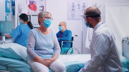 Mature Patient Speaking With Doctor in Hospital Room