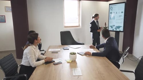 Business Meeting in Office Young Businessman Speak at a Meeting and Shows Financial Infographic in