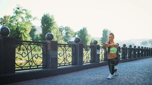 Active woman exercising and stretching in city park