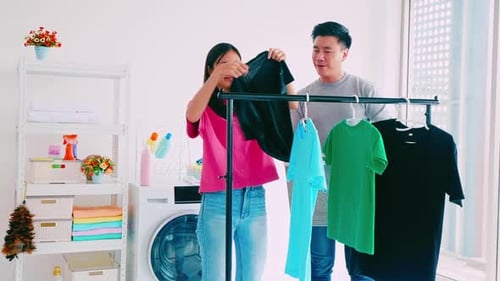 Couple Hanging Laundry on Rack Indoors