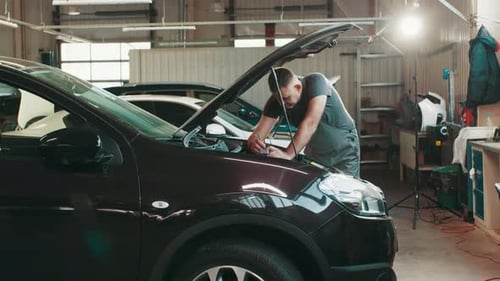 Man Repairing Car Engine in Auto Shop