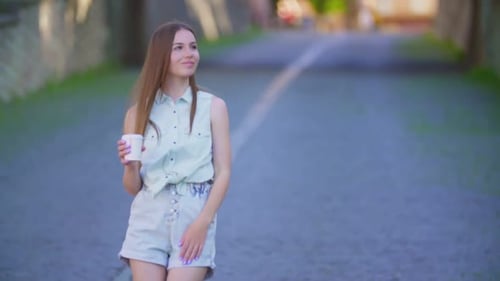 Attractive Woman Walking on City Street With Coffee