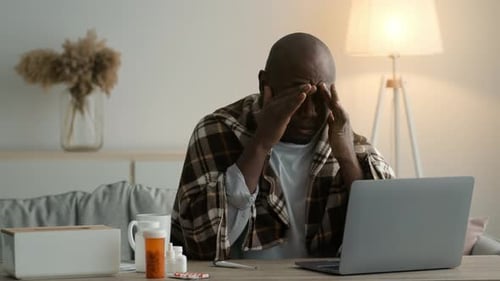 Sick African Man Rubbing Sore Eyes Sitting At Laptop Indoors