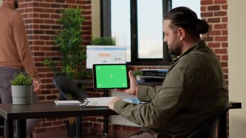 Man Holds Tablet with Green Screen in Office
