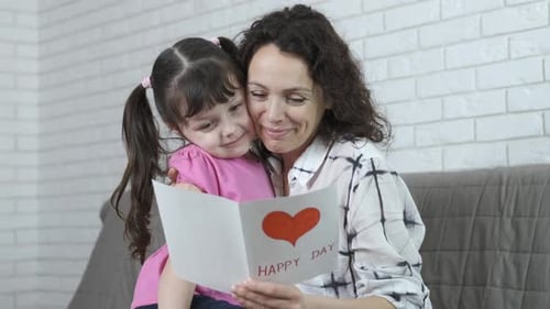 Loving Child Giving Card to Mother on Birthday