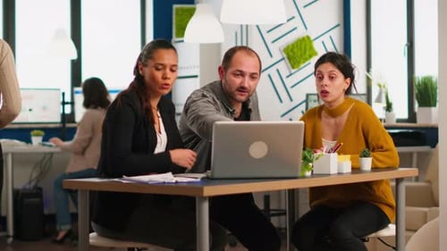 Young Adults Collaborating on Laptop in Modern Office