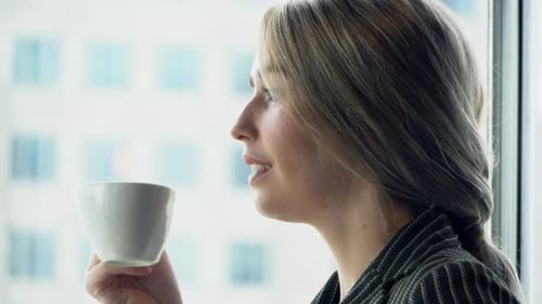 Beautiful young businesswoman confident drinking coffee for leisure after work at window in office.
