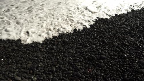 Black Pebbles by the Beach Shore with Waves