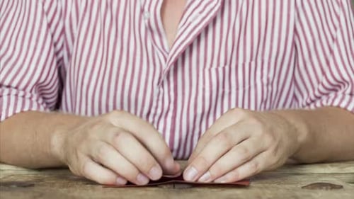 Adult Making Origami Red Heart on Table