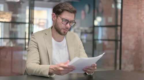 Man Reviews Documents in Modern Office Setting