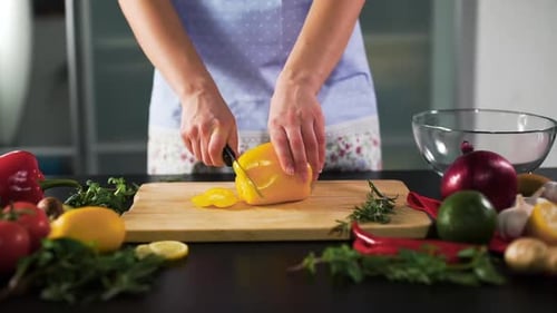 Woman Slicing Yellow Bell Pepper in Kitchen