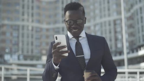 Man Smiles Using Phone Outside Office Building