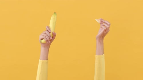 Condom Applied to Banana on Yellow Background