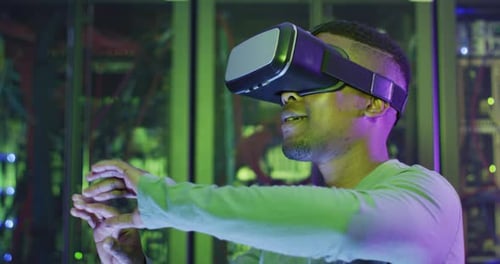 African american male computer technician using vr headset working in business server room