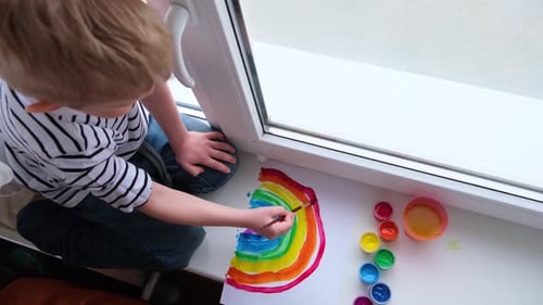 Child Paints a Colorful Rainbow on Windowsill