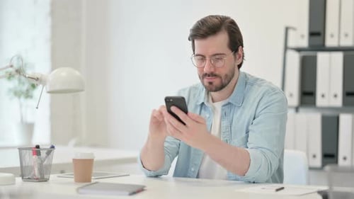 Joven atractivo que usa un teléfono inteligente funciona