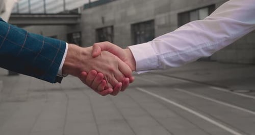 Close Up of the Hands of Top Managers in Business Suits Shake Hands with Each Other Near Building