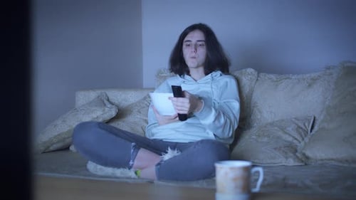 Young Adult Watching TV with Popcorn at Night
