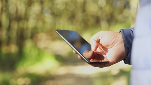Nahaufnahme einer Person, die ein Smartphone im Wald benutzt