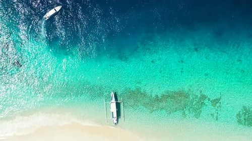 Wide flying travel shot of a sandy white paradise beach and aqua blue water background